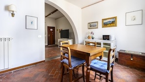 Un comedor con una mesa y sillas de madera, un armario blanco y un televisor al fondo.