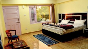 Un dormitorio con cama, ventana, puerta, una mesita pequeña y una silla.