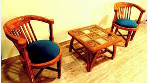 Dos sillas de madera con cojines azules y una pequeña mesa con cubierta de vidrio y diseños florales.