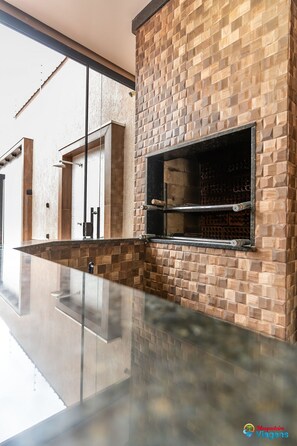 Cozinha moderna com painel de parede de tijolos, bancada de vidro e forno embutido.