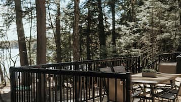 An outdoor deck with a wooden table and chairs, surrounded by a metal railing.