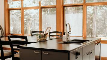 A modern kitchen with a central island, a sink, and a dining area with chairs.