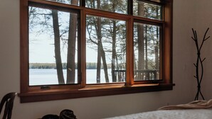 Une chambre avec une grande fenêtre donnant sur une forêt et un lac.