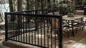 Un espace extérieur aménagé pour les repas, avec une terrasse en bois, une rambarde en métal et des sièges.