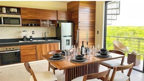 Une cuisine moderne avec des meubles en bois, un four encastré et un coin repas aménagé pour six personnes, avec une table et des chaises.