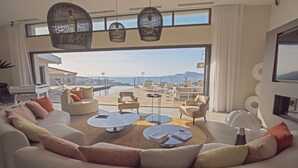A modern living room with a large sofa, coffee tables, and wicker hanging lights. - Villa Clémentines Porticcio (Grosseto-Prugna)