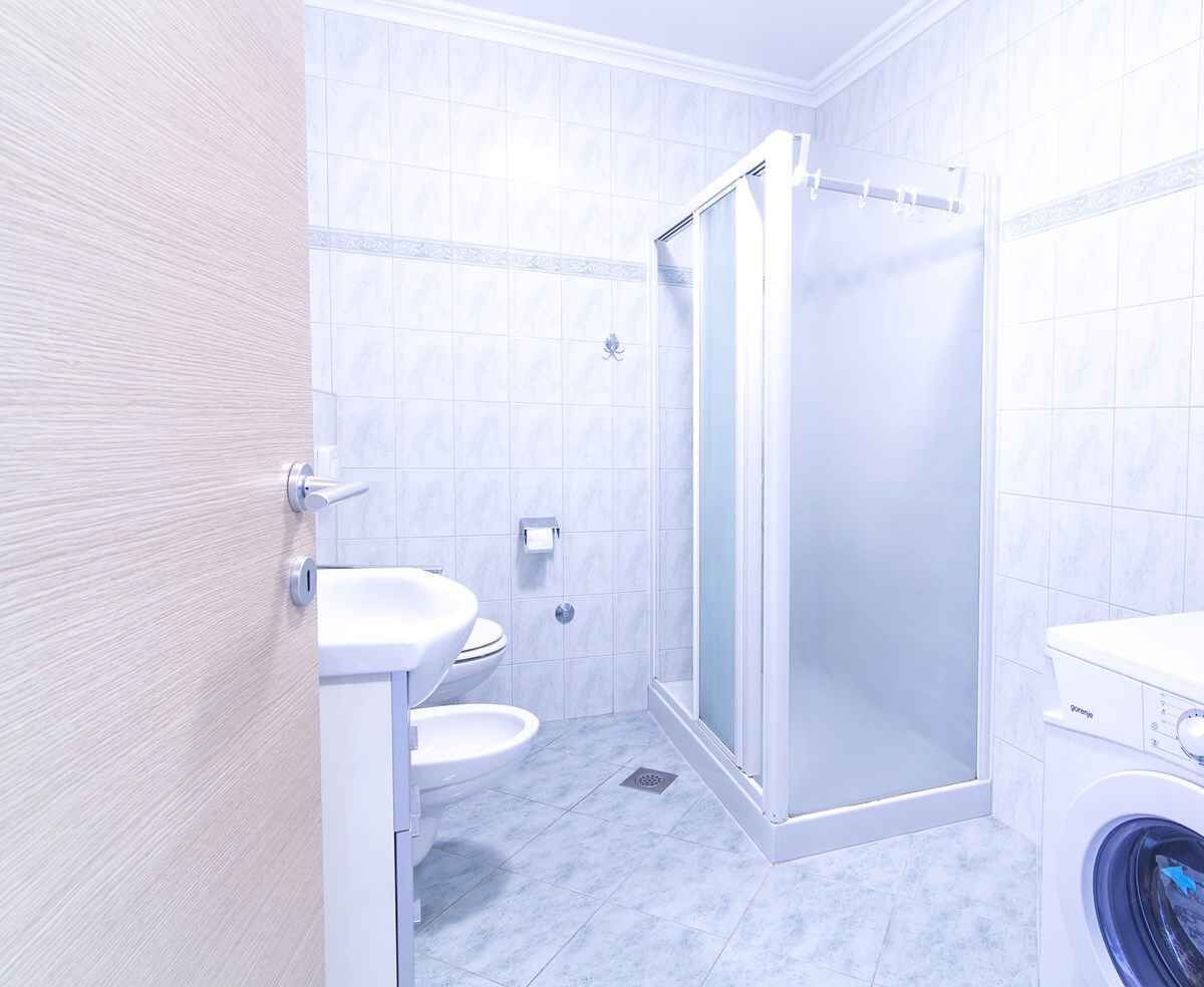 Une salle de bain équipée de toilettes, d’un lavabo, d’une douche et d’un lave-linge.