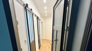 Un pasillo estrecho con suelo de madera y puertas a ambos lados.