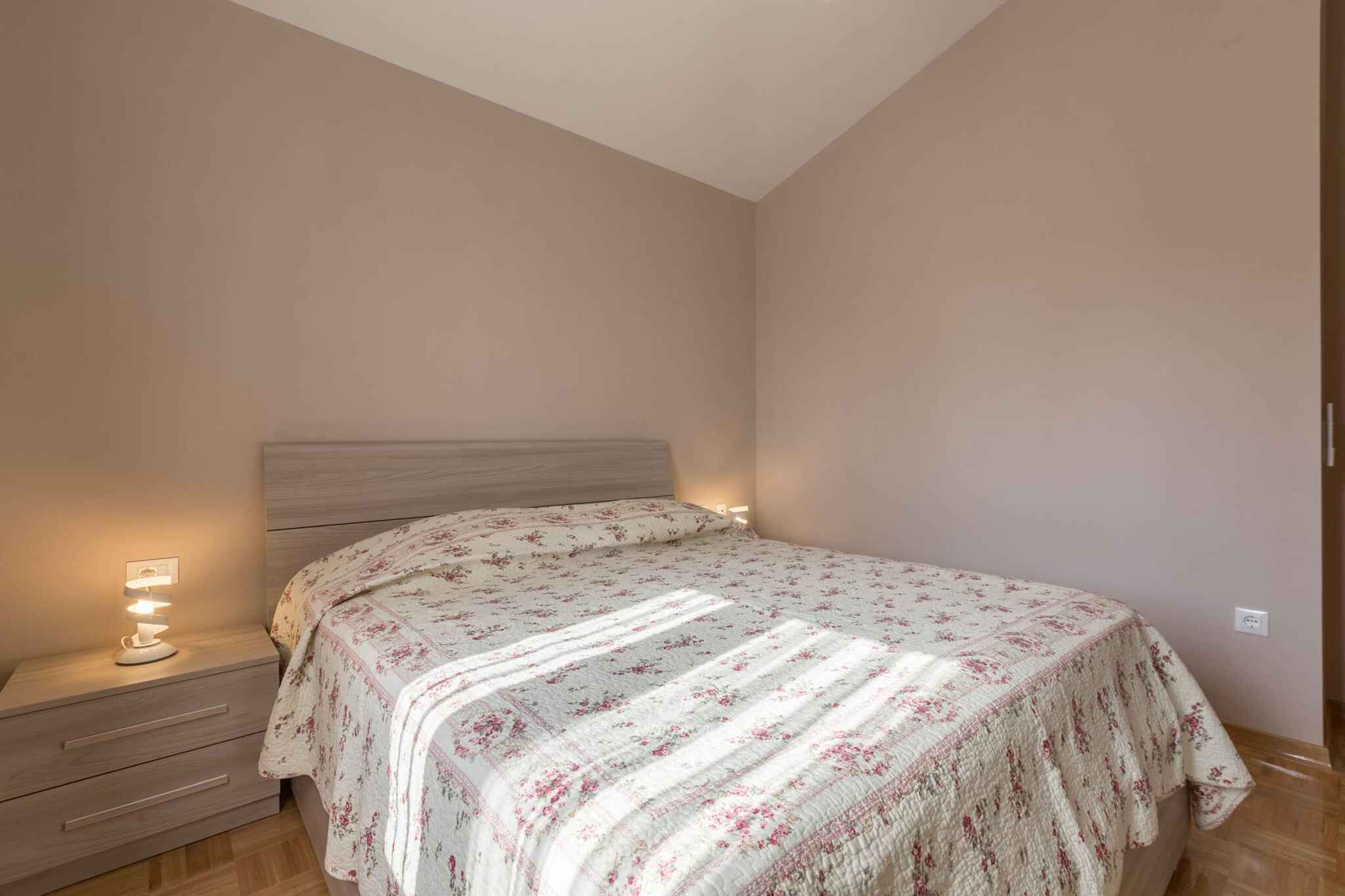 Un dormitorio con cama, mesita de noche y luz empotrada en la pared.