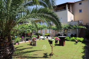 A courtyard with a palm tree, potted plants, and a small table. - Holiday flat with air conditioning (Pula)
