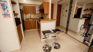 Una cocina moderna con armarios de madera, una isla central y dos taburetes de bar.