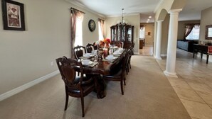 A dining room with a long wooden table set for six, flanked by chairs.