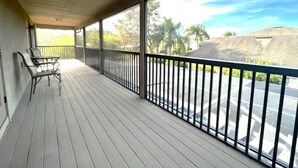A covered balcony with a railing, a table, and chairs.