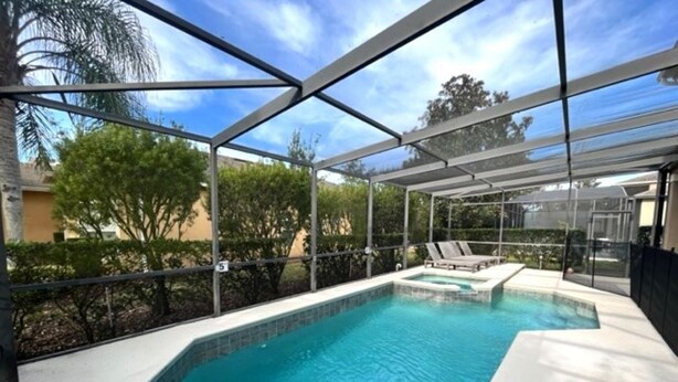 A swimming pool with a glass enclosure, surrounded by a white deck and a metal frame.