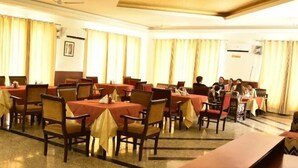 A dining area with multiple tables and chairs, arranged in rows. - Dabchick Tourist Resort (Hodal)