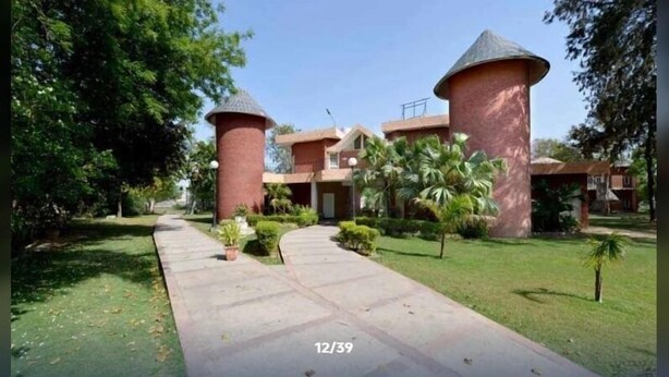 A building with two cylindrical towers, a paved walkway, and surrounding greenery. - Dabchick Tourist Resort (Hodal)