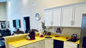 A modern kitchen with white cabinets, a yellow countertop, and a stainless steel refrigerator.