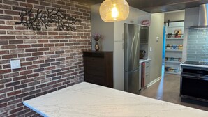 Una cocina con pared de ladrillo, electrodomésticos de acero inoxidable y encimera de mármol.