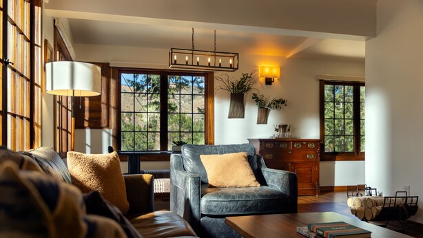 A living room with a sofa, armchair, wooden coffee table, books, and a fireplace. - Serene Mountain View Cabin w/ Deck, Hot Tub, Fire Pit, Forest & Peak Retreats (Cascade-Chipita Park)
