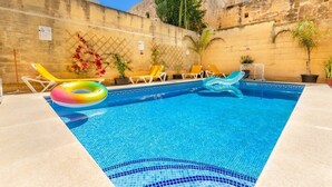 Una piscina con sillas de descanso y una palmera.
