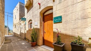 Un estrecho callejón con un edificio de piedra, una puerta de madera y un cartel que anuncia una estancia rural.