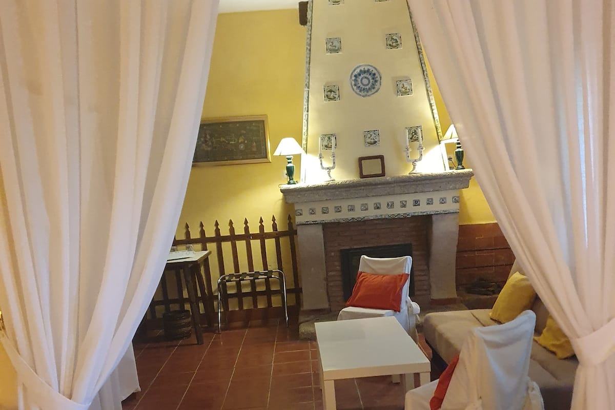 Una sala de estar acogedora con chimenea, un sofá, una mesita y un sillón.