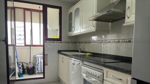 Una cocina con armarios blancos, estufa, horno y lavavajillas.
