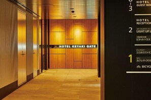 A hotel reception area with a wooden door labeled 'HOTEL KEYAKI GATE' and a directory on the right side. - Hotel Keyaki Gate Tokyo Fuchu (Fuchu)