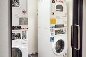 A laundry facility with multiple washing machines and dryers, including a digital control panel.