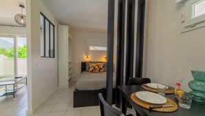 Habitación de hotel moderna con una cama, un rincón de comedor con una mesa preparada para dos personas y vistas al exterior.