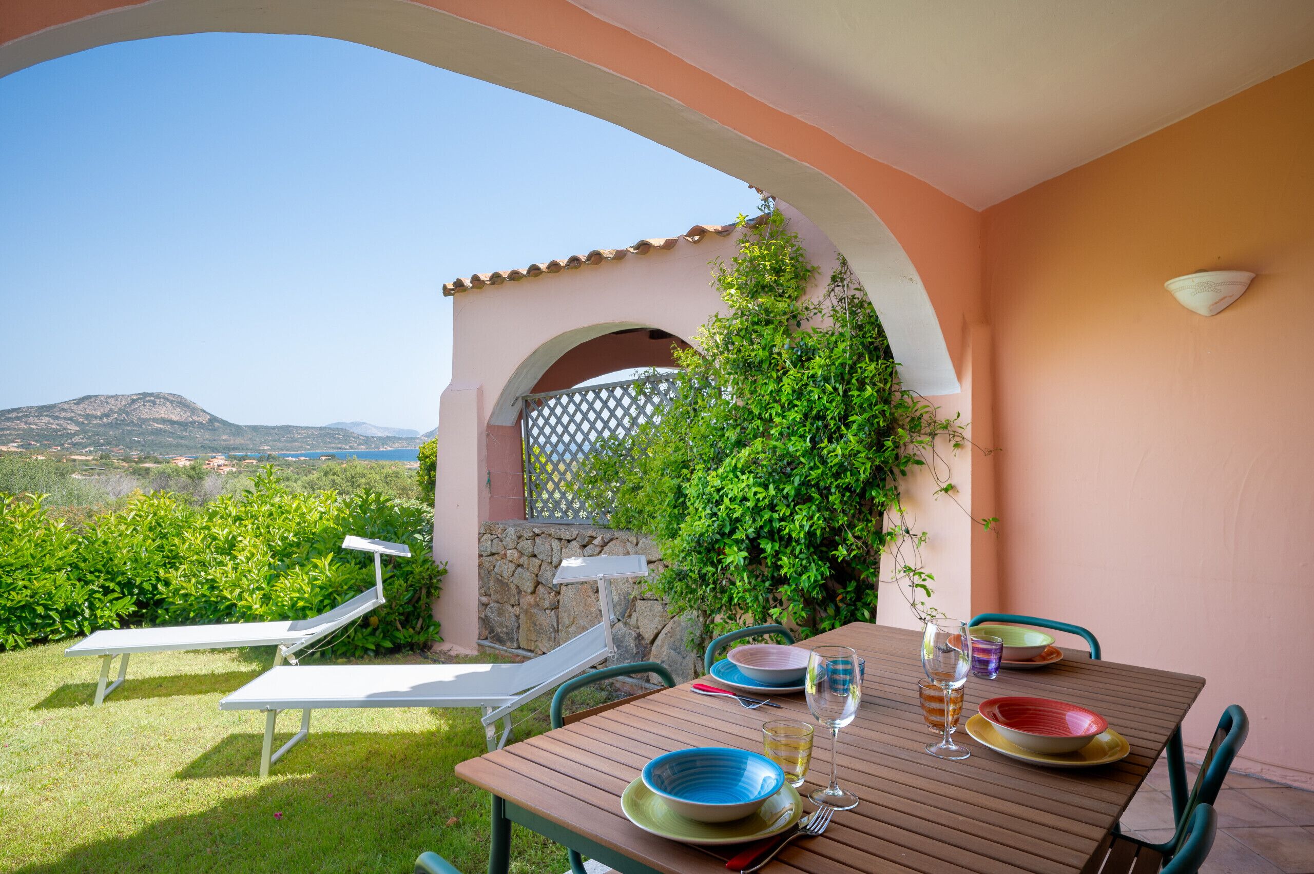 An outdoor dining area with a table set for two, overlooking a mountainous landscape.