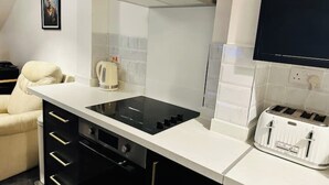 A modern kitchen with a black stove, white cabinets, and a white countertop. - 1 Luxe Exec Bedroom Apt Derby (Derby)