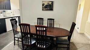 A dining area with a round table and six chairs, a microwave, and a radiator on the wall. - 1 Luxe Exec Bedroom Apt Derby (Derby)