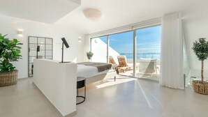 Un dormitorio moderno con una cama, un escritorio y un balcón con sillas.