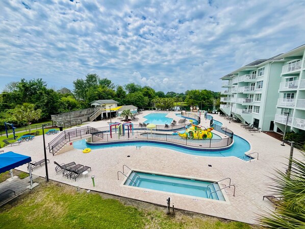 A resort with multiple swimming pools, a playground, and a building with balconies.