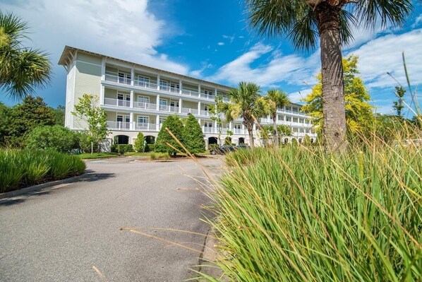 Un hotel a più piani con un cortile centrale, circondato da vegetazione lussureggiante e palme.