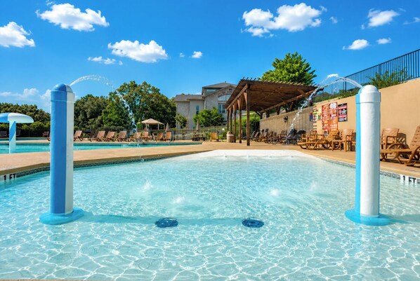 A swimming pool with lounge chairs, a covered seating area, and a building in the background. - Family Fun Resort. Enjoy Pools, Hot Tub, Golf, Game Room, Fishing, Karaoke (Branson)
