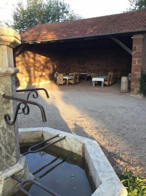 Guests can dine al fresco in this charming outdoor space, surrounded by a water feature and a gravel path.