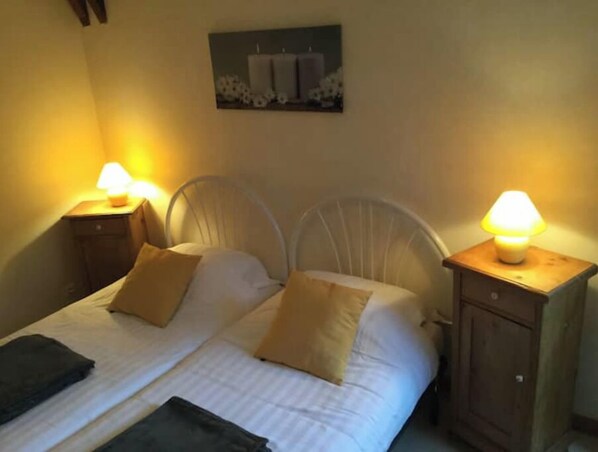 A bed with white bedding, two pillows, and two bedside tables with lamps.