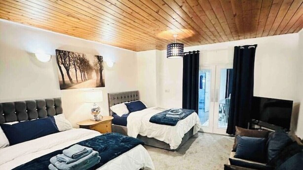 Een slaapkamer met twee bedden, een slaapbank, een televisie en een plafondlamp.