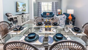 A dining area with a glass table set for six, surrounded by wicker chairs. - 'Sunshine State of Mind' South Facing Pool & Spa (Clermont)