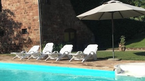 A swimming pool with white lounge chairs and a large umbrella. - Chambre D'hôtes Référence® "La Valse" + Jacuzzi (Conques-en-Rouergue)