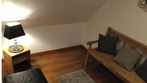 A cozy room with a wooden bench, a small table with a lamp, and a rug on the wooden floor. - Chambre D'hôtes Référence® "La Valse" + Jacuzzi (Conques-en-Rouergue)