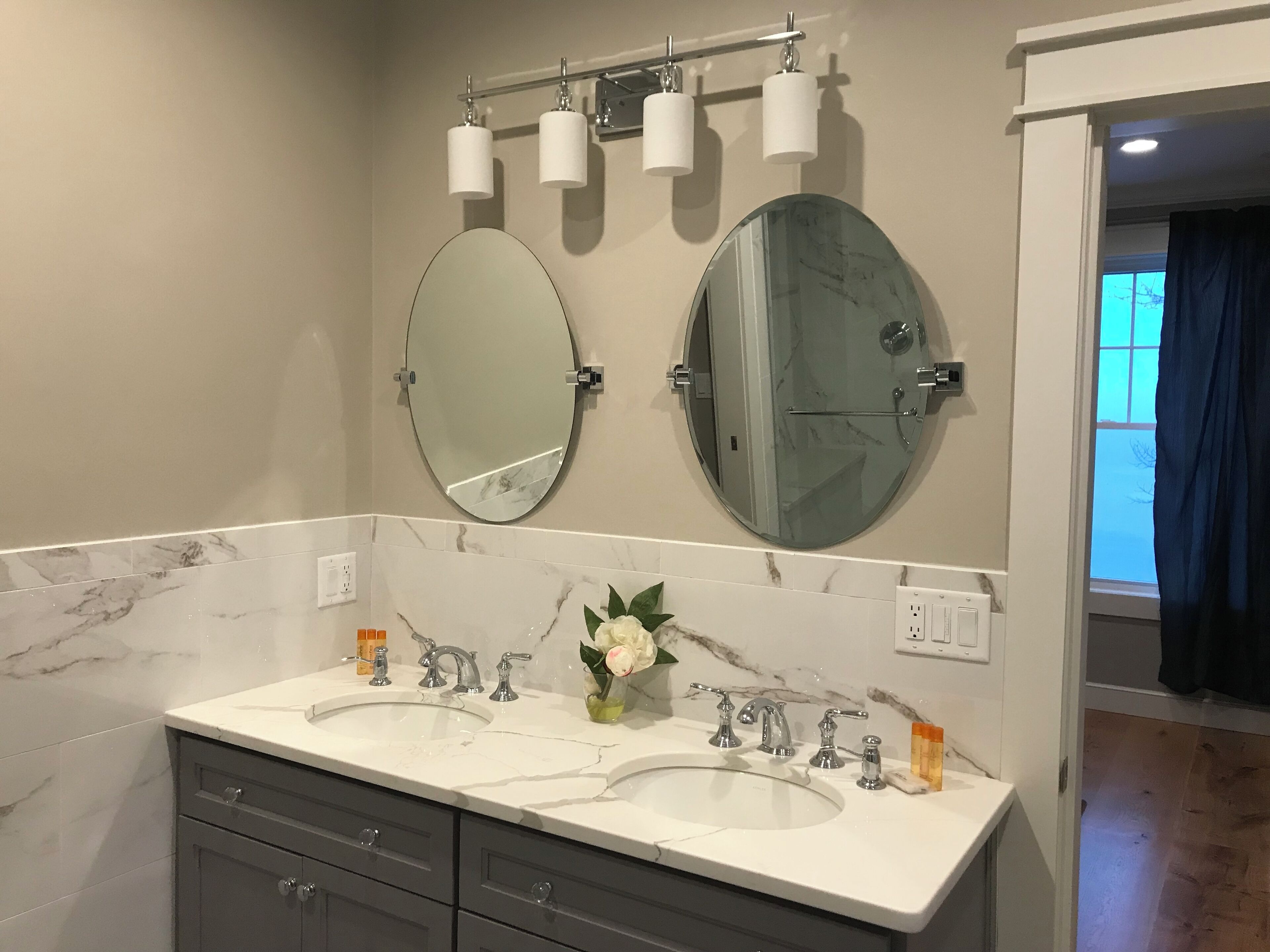 Une salle de bain avec deux lavabos, un grand miroir et un porte-serviettes avec trois serviettes.