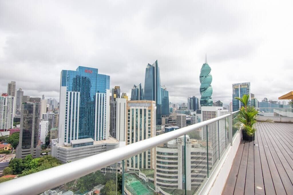 A cityscape with modern high-rise buildings, a distinctive twisted tower, and a wooden deck with a railing.