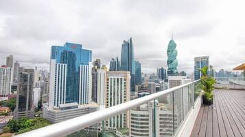 A cityscape with modern high-rise buildings, a distinctive twisted tower, and a wooden deck with a railing.
