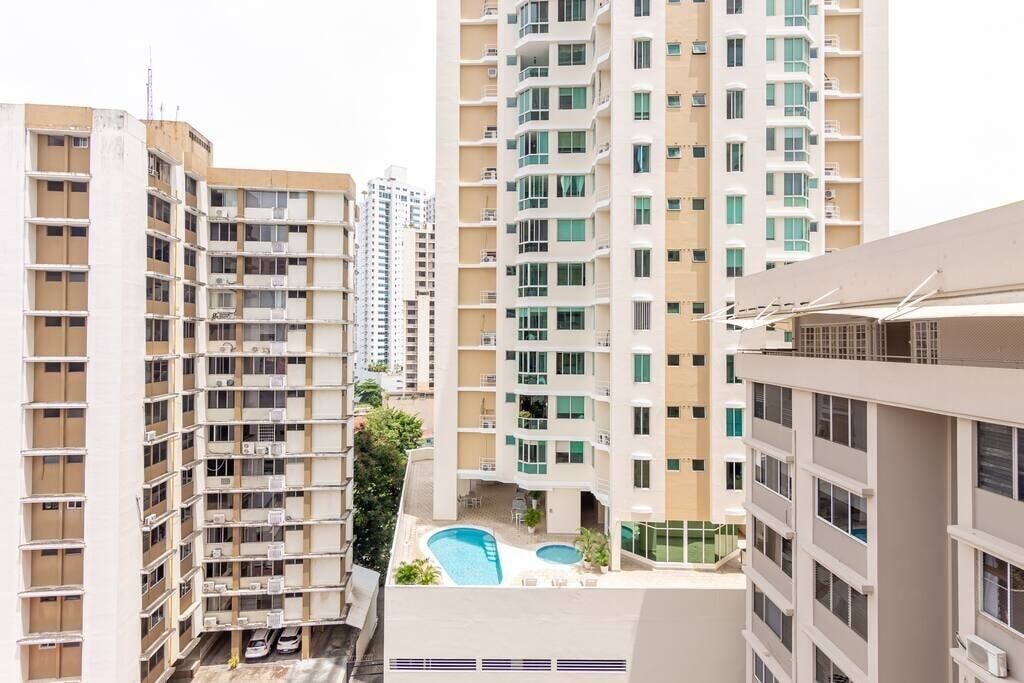 A high-rise residential building with multiple balconies, a rooftop pool, and a modern architectural design.