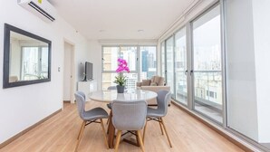 A modern living room with a round table, grey chairs, a potted plant, and a sofa.