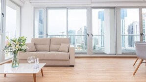 A spacious living room with a beige sofa, a white coffee table, and a vase of flowers.