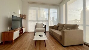 Una sala de estar moderna con televisor, sofá y mesa de centro.